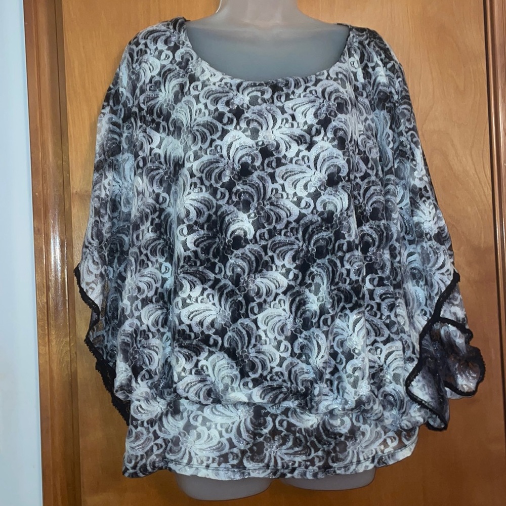 White lace overlay top. Black lining. Wing sleeves trimmed in black
